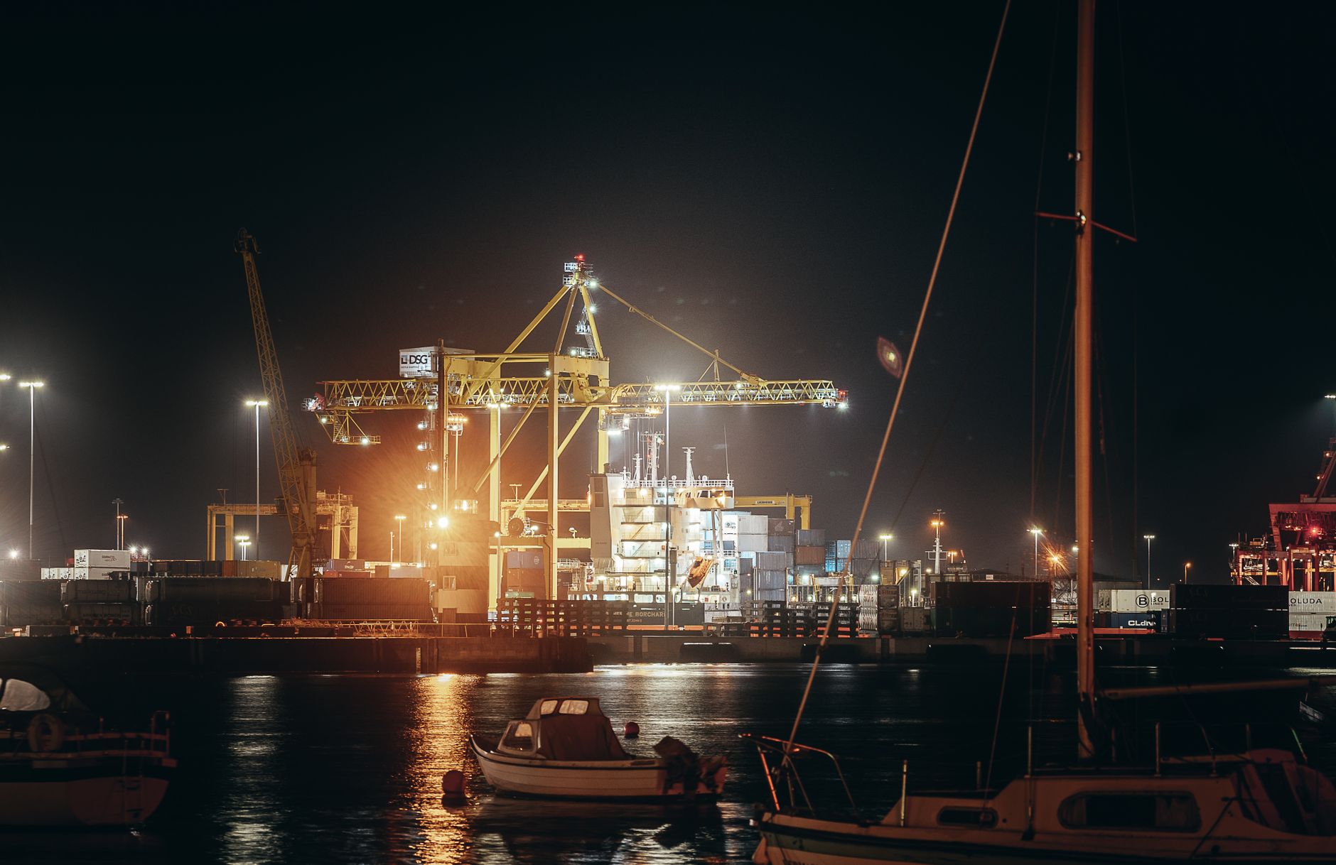 Porto de contêineres iluminado à noite, com guindastes em operação